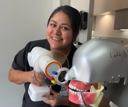 Smiling Georgetown DAS student practicing her first dental X-rays using a training mannequin during week 3